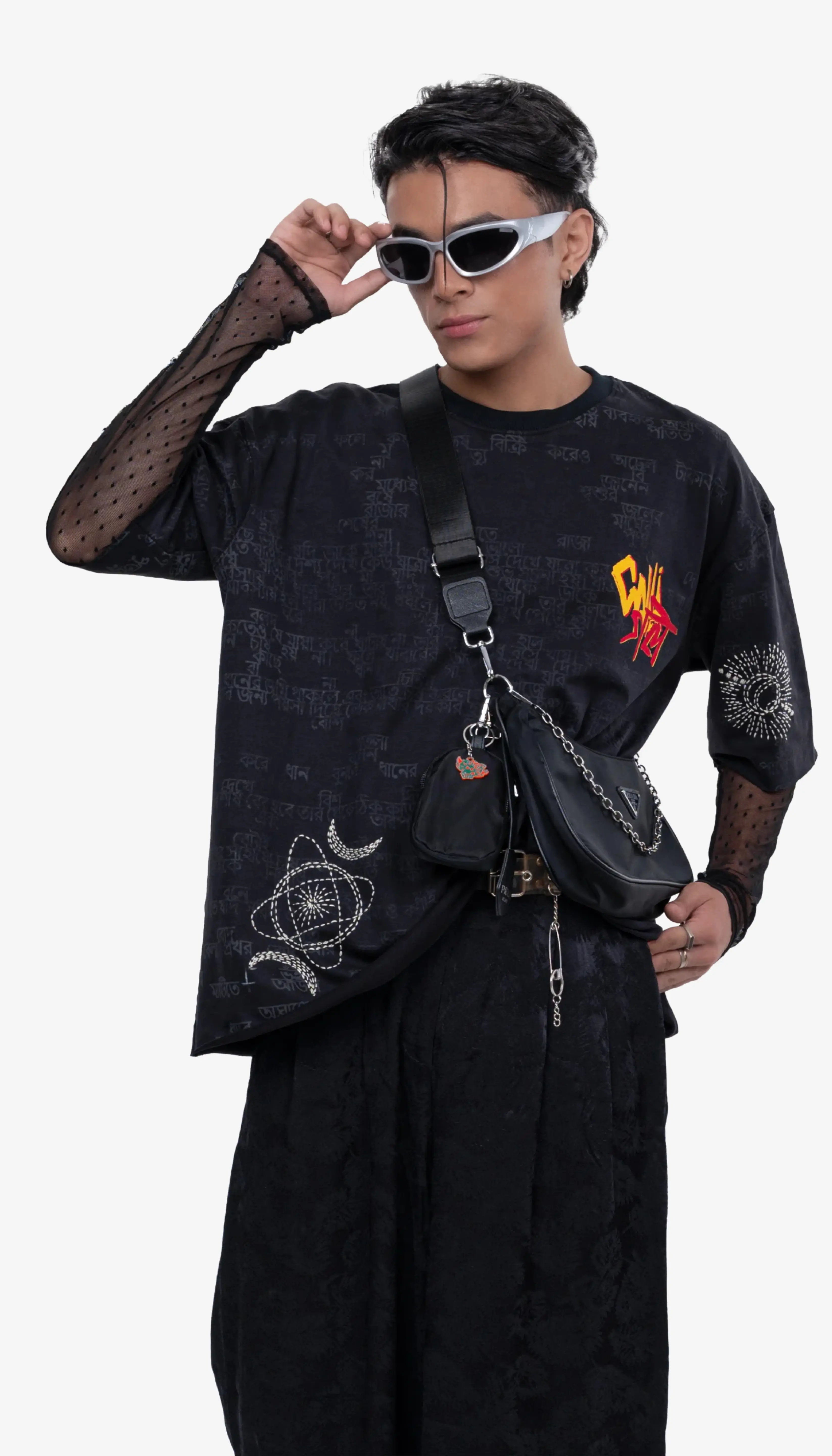 Person wearing a black outfit with unique designs, holding sunglasses, on a white background