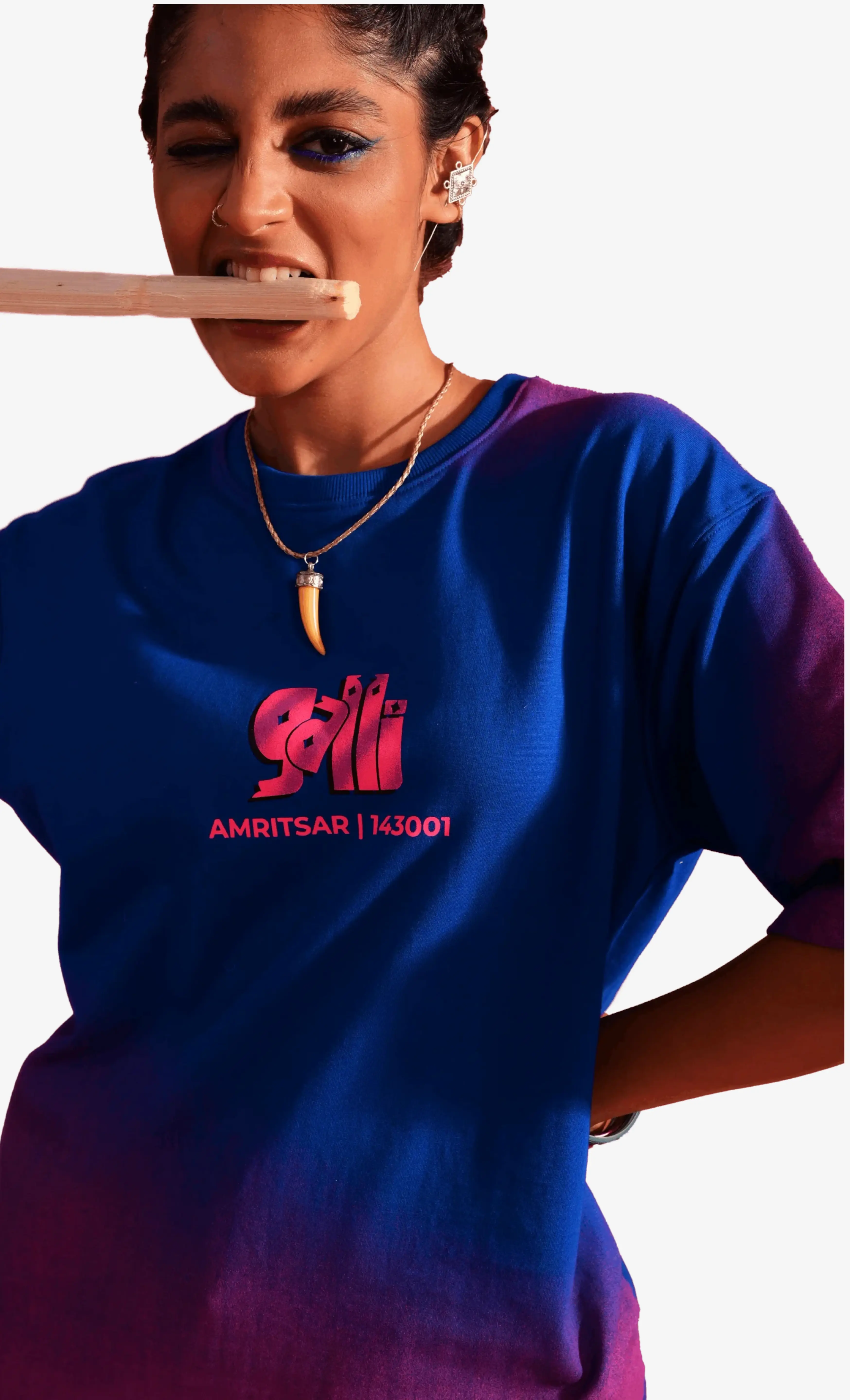 Person wearing a blue Sattva and Sage t-shirt with a logo and text, holding a wooden object.