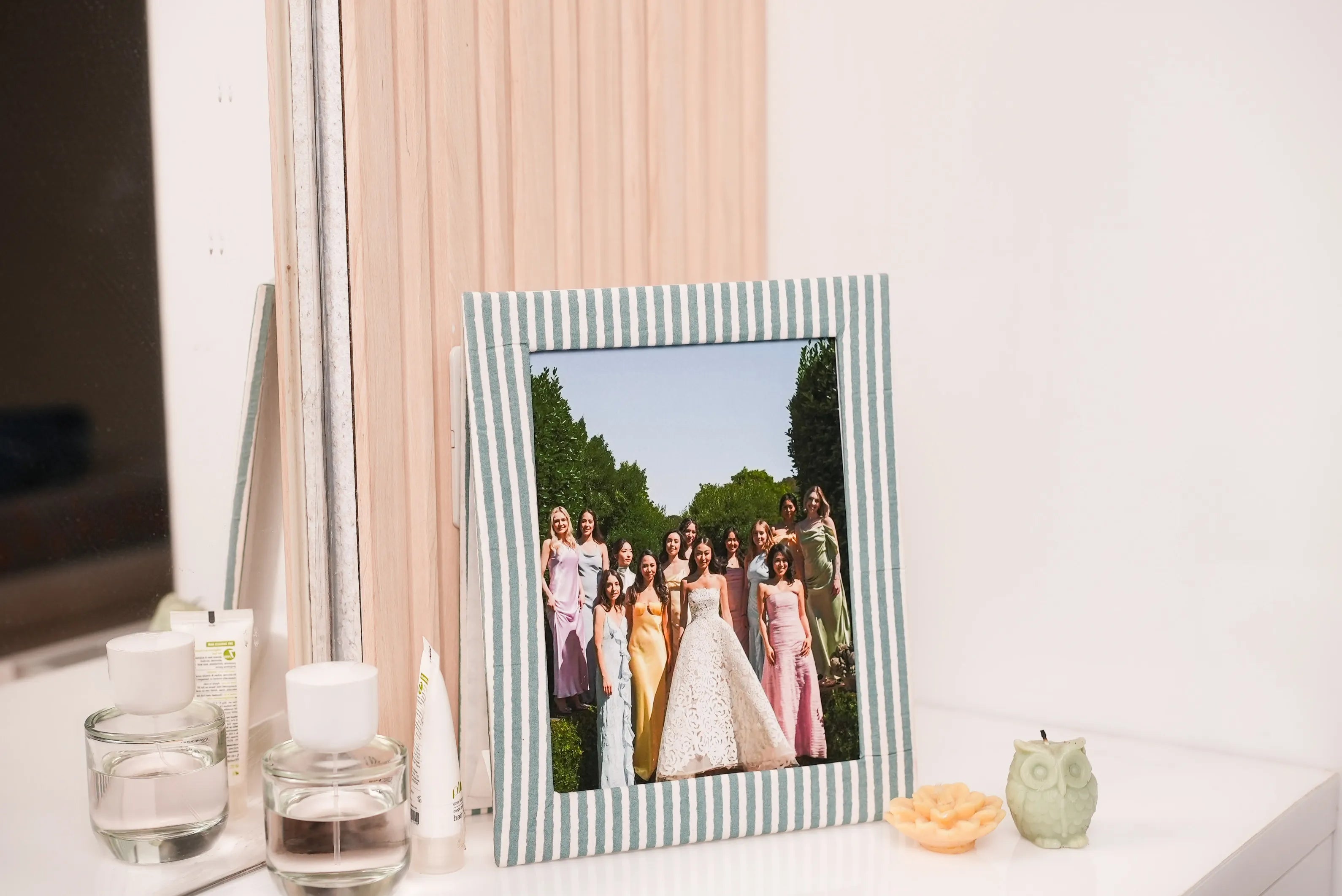 Stripped photo frame with a wedding photo on a table with candles and a vase.