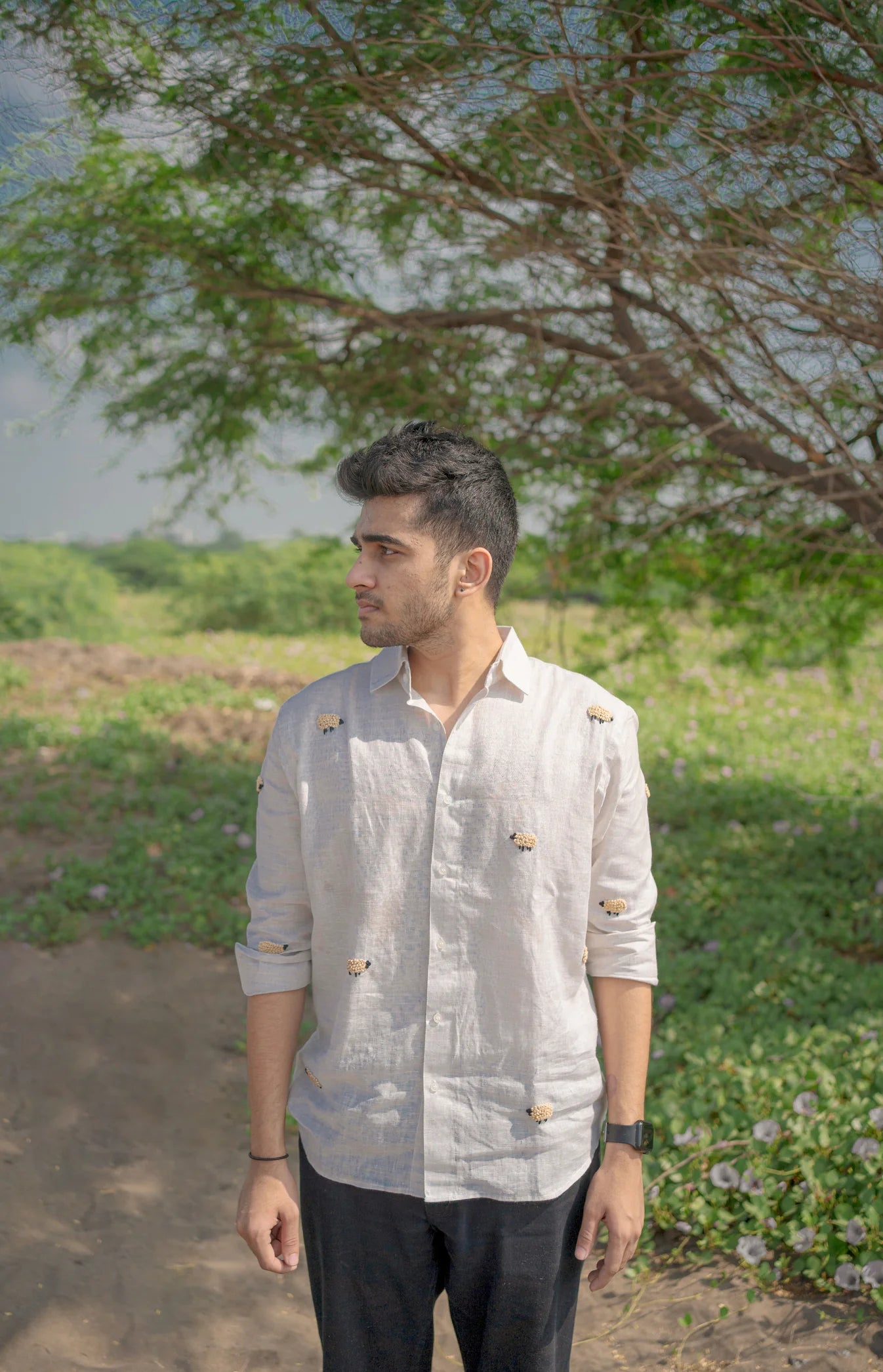 Man wearing a light-colored shirt with buttons in a natural setting