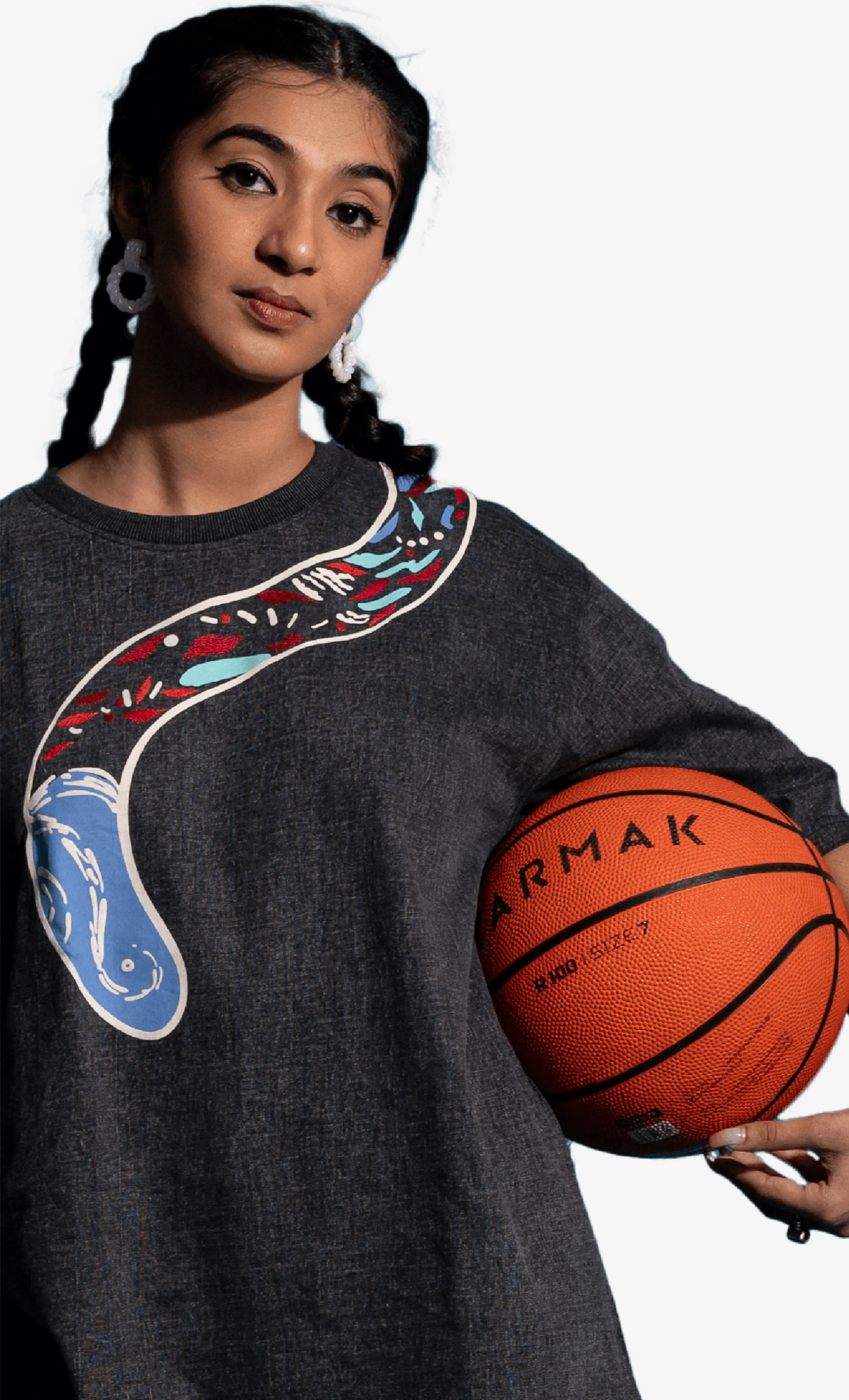 Person wearing a dark gray Sattva and Sage sweatshirt with colorful designs, holding a basketball.