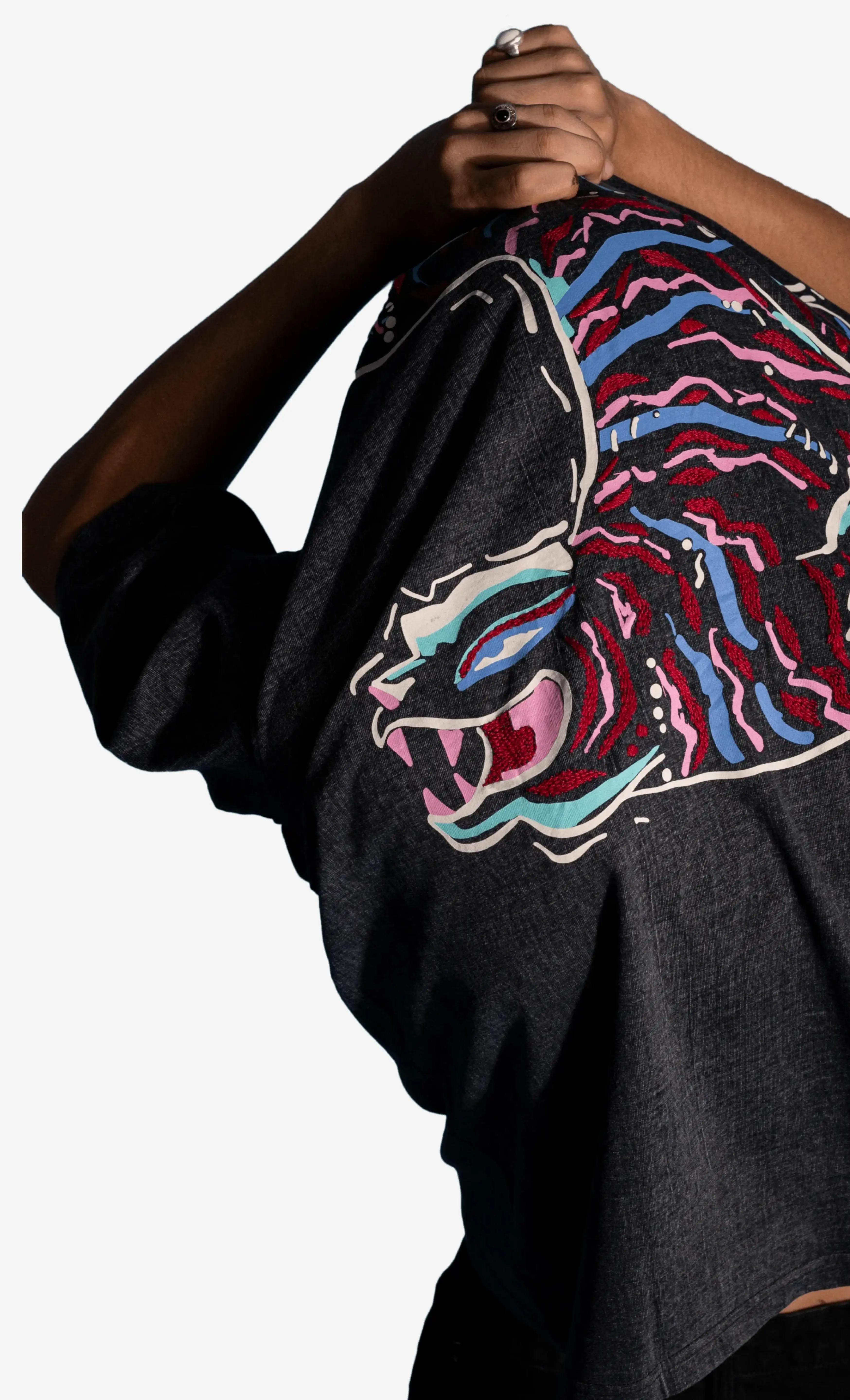 Black Sattva and Sage t-shirt with a colorful graphic design held by a person against a white background.