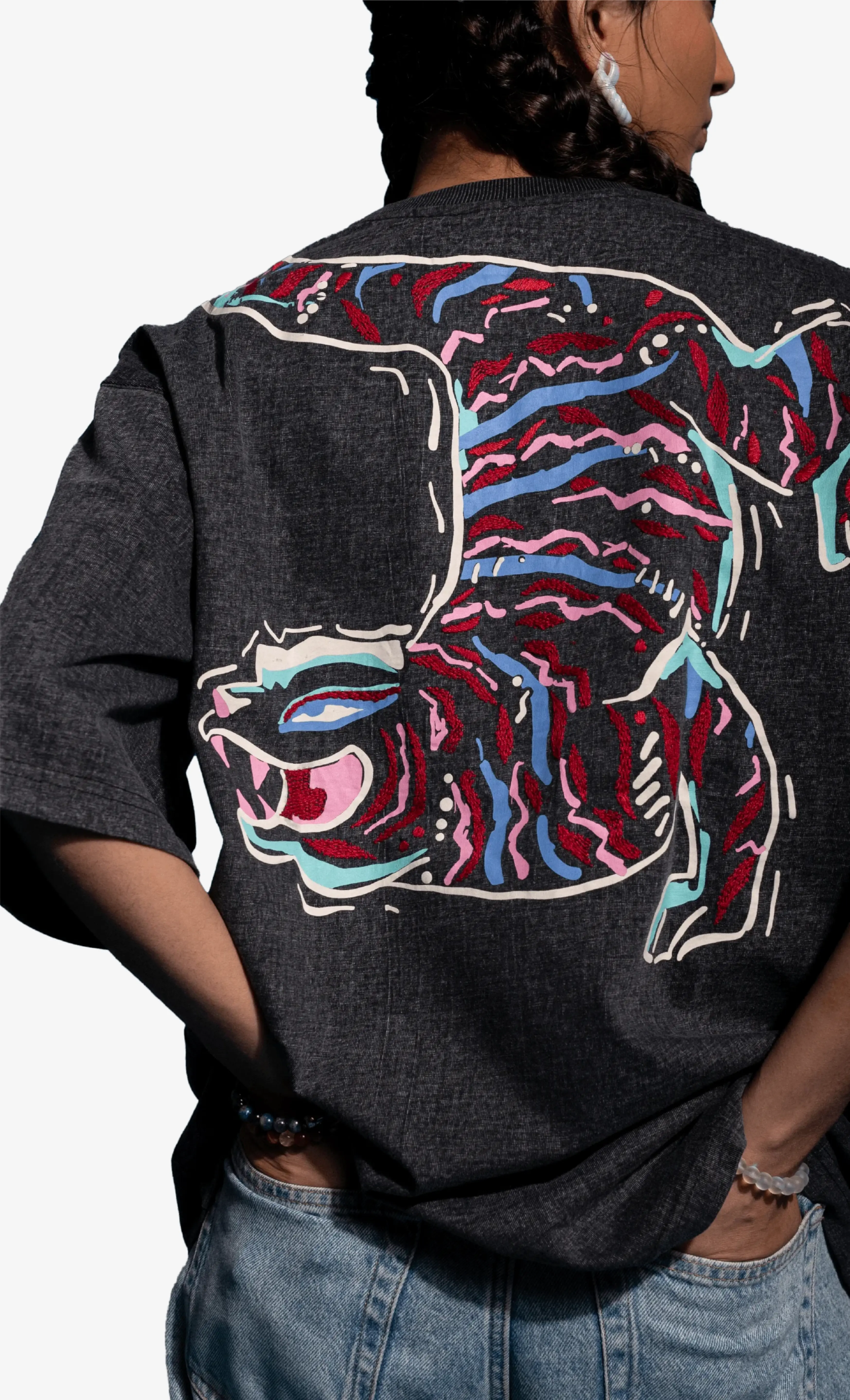 Person wearing a dark gray Sattva and Sage jacket with a colorful tiger design on the back.