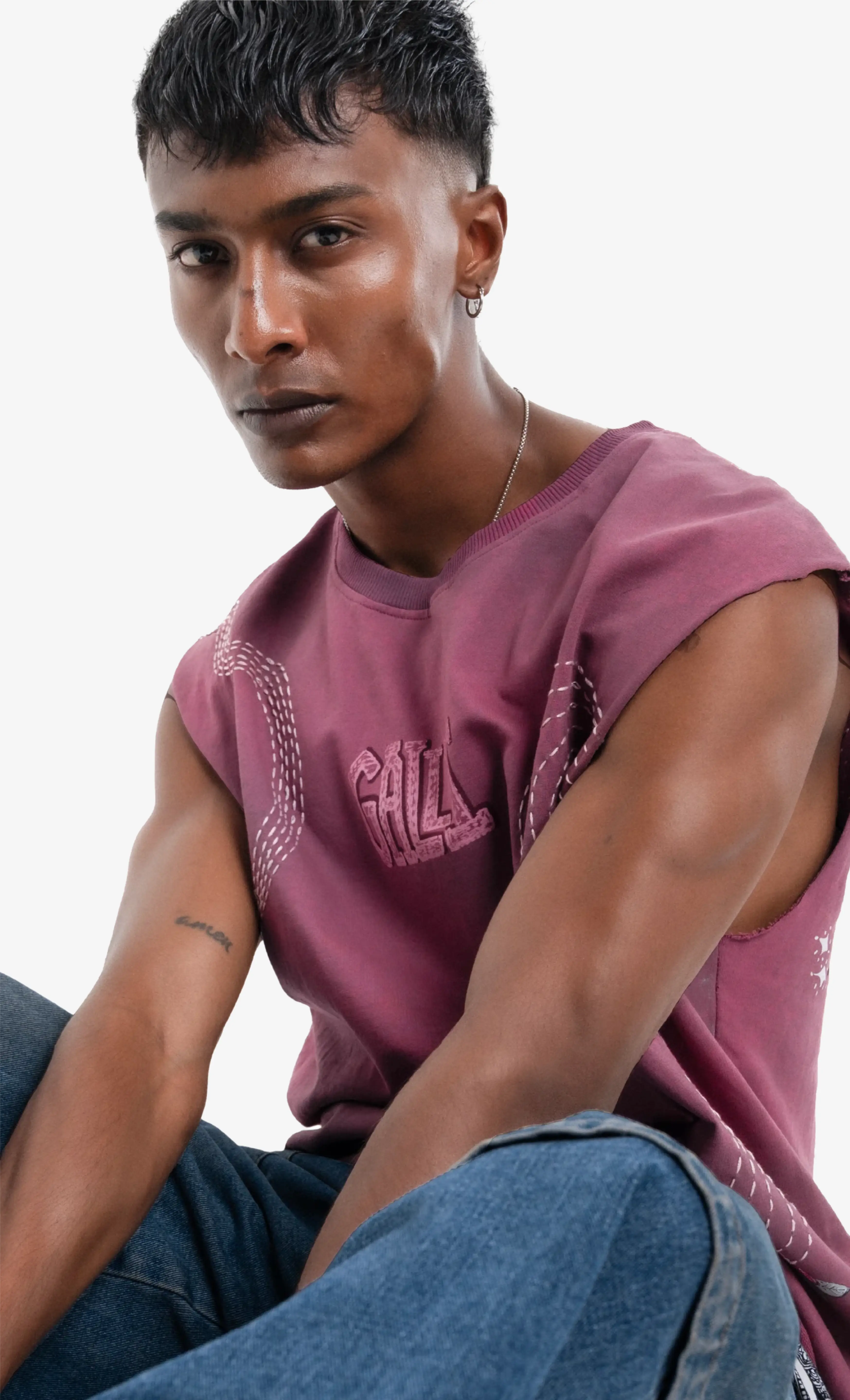 Man wearing a pink t-shirt with text and blue jeans on a white background